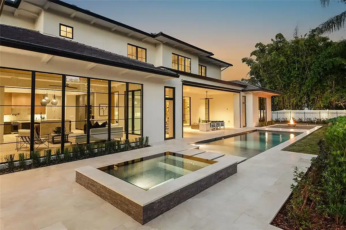 Pool and spa glowing at dusk behind a new Winter Park home